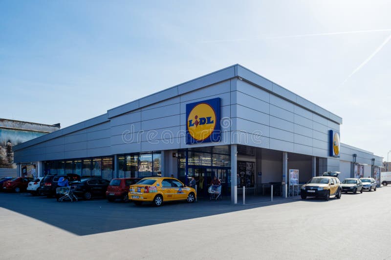 Le supermarché de Lidl avec des voitures a garé la lentille large de achat de personnes photos stock Le supermarché de Lidl avec des voitures a garé la lentille large de achat de personnes photos stock