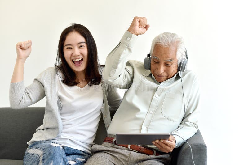 Le temps heureux de famille, la fille asiatique de sourire et le père plus âgé ont plaisir à observer le film à partir de l'ordin photographie stock Le temps heureux de famille, la fille asiatique de sourire et le père plus âgé ont plaisir à observer le film à partir de l'ordin photographie stock