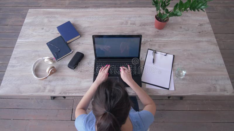 Le texte de dactylographie d'étudiante sur le clavier d'ordinateur portable et écrit des notes dans le presse-papiers se reposant