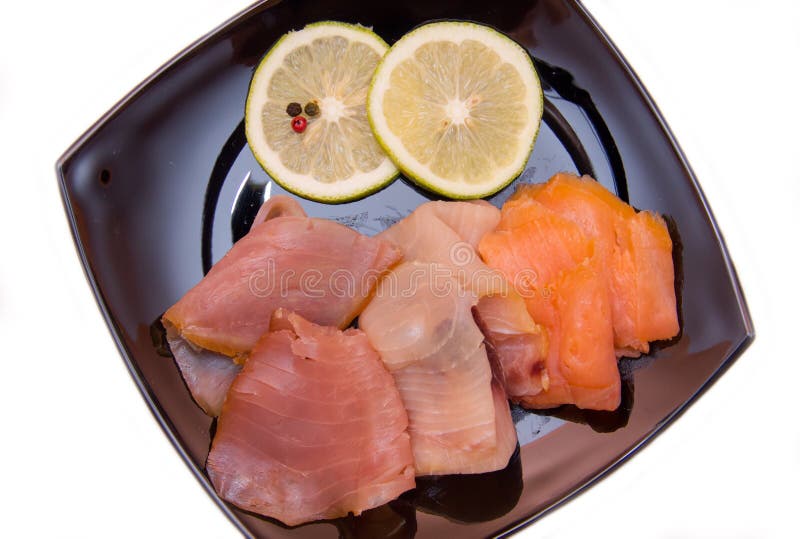 Trio of smoked fish on plate on white background seen from above and close. Trio of smoked fish on plate on white background seen from above and close