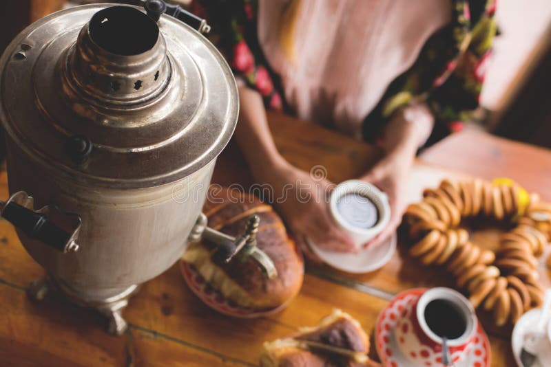 Le thé, les plats russes traditionnels et les festins, un samovar sur la table, les mains d'une femme dans un foulard national ti photo stock Le thé, les plats russes traditionnels et les festins, un samovar sur la table, les mains d'une femme dans un foulard national ti photo stock