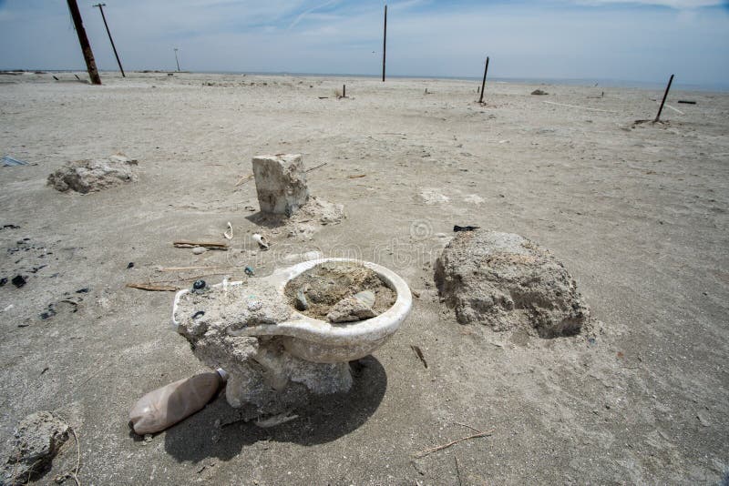 Le toliet abandonné se repose enterré dans le sable en plage la Californie, une ville abandonnée de Bombay à la mer de Salton images libres de droits Le toliet abandonné se repose enterré dans le sable en plage la Californie, une ville abandonnée de Bombay à la mer de Salton images libres de droits