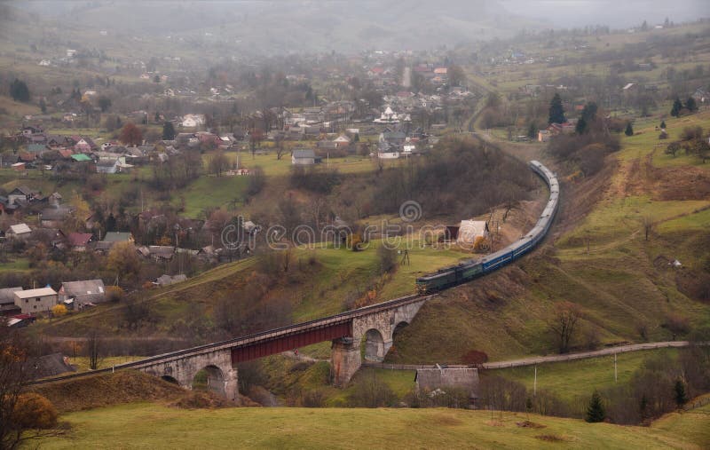 Le train monte sur un chemin de fer de enroulement Autumn Rural Landscape With Locomotive, viaduc ferroviaire, montagnes et un vi photo libre de droits