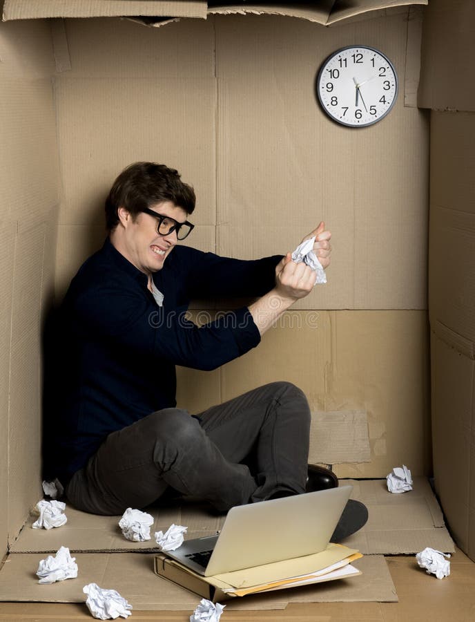Le travailleur fâché déchire le papier à l'intérieur de la petite boîte en carton photo stock Le travailleur fâché déchire le papier à l'intérieur de la petite boîte en carton photo stock