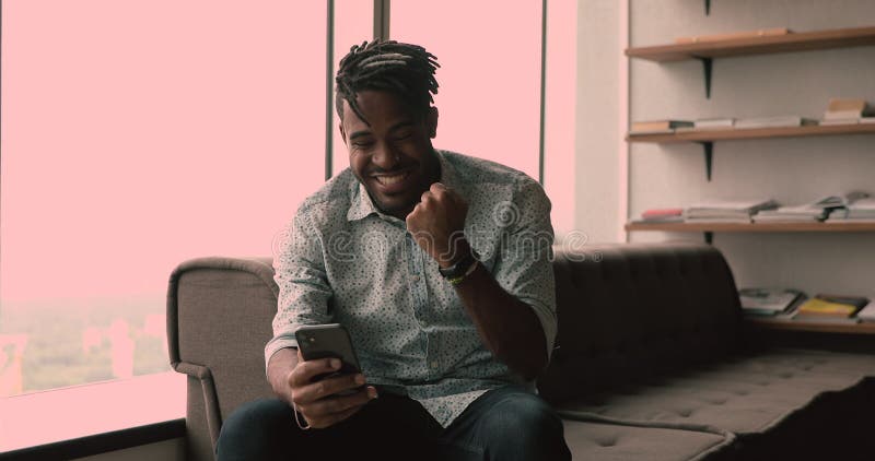 Le type africain heureux reçoivent des sms sur le portable célèbrent une grande nouvelle banque de vidéos