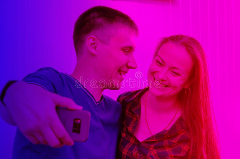 Le type avec la coupe de cheveux courte dans le T-shirt et la fille de sourire avec de longs cheveux foncés dans la chemise à car photographie stock libre de droits Le type avec la coupe de cheveux courte dans le T-shirt et la fille de sourire avec de longs cheveux foncés dans la chemise à car photographie stock libre de droits