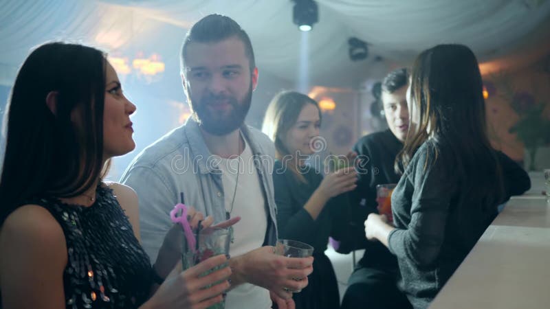 Le type avec une barbe flirte avec une fille près du compteur de barre avec des cocktails dans le club