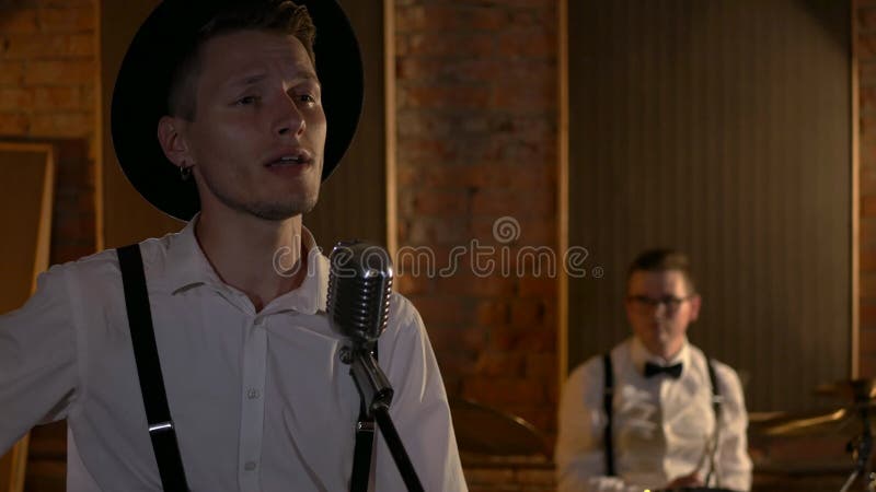 Le type chante et joue de la guitare au studio. le groupe musical joue au restaurant. la nuit est une lumière romantique.