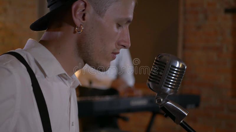 Le type chante et joue de la guitare au studio. le groupe musical joue au restaurant. la nuit est une lumière romantique.