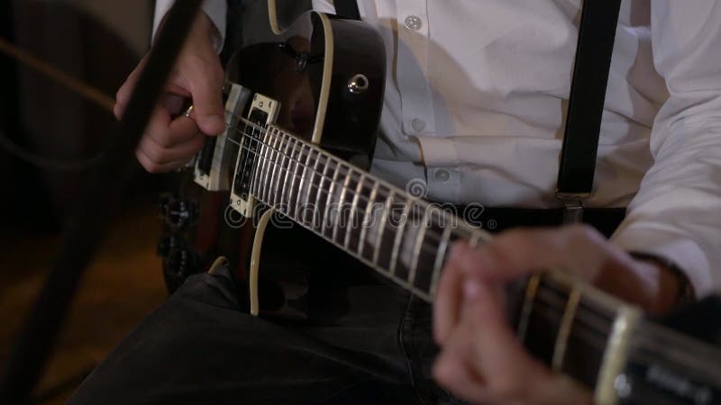 Le type chante et joue de la guitare au studio. le groupe musical joue au restaurant. la nuit est une lumière romantique.