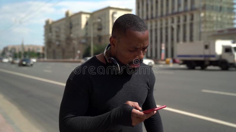 Le type smartphone utilise le noir en marchant dans la rue de la ville à la lecture d'été et aux messages de typage banque de vidéos