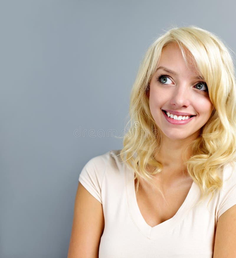 Smiling blonde caucasian woman looking up on grey background. Smiling blonde caucasian woman looking up on grey background