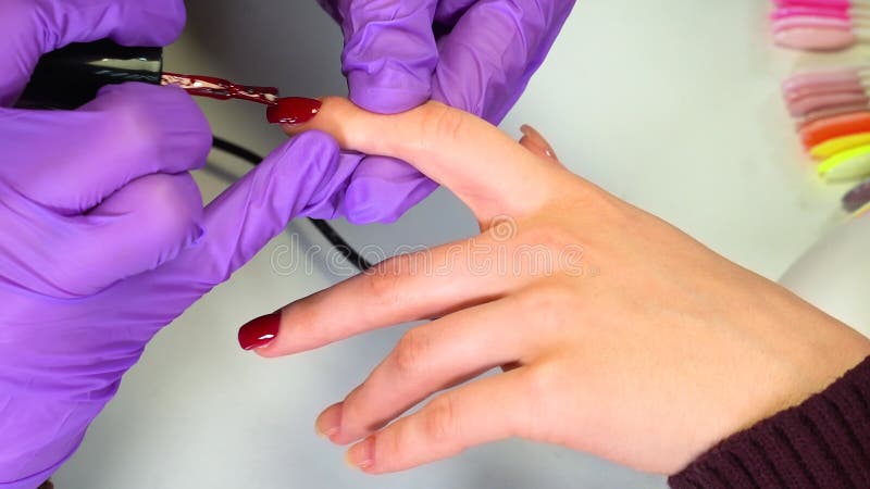 Le unghie sulla mano di una donna sono dipinte con una lacca rossa nel salone di bellezza. unghia manicure per donna nel master pr