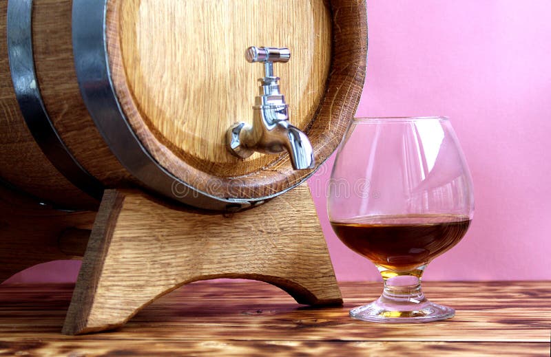 Le verre d'eau-de-vie fine sur le fond du chêne barrels photos stock Le verre d'eau-de-vie fine sur le fond du chêne barrels photos stock