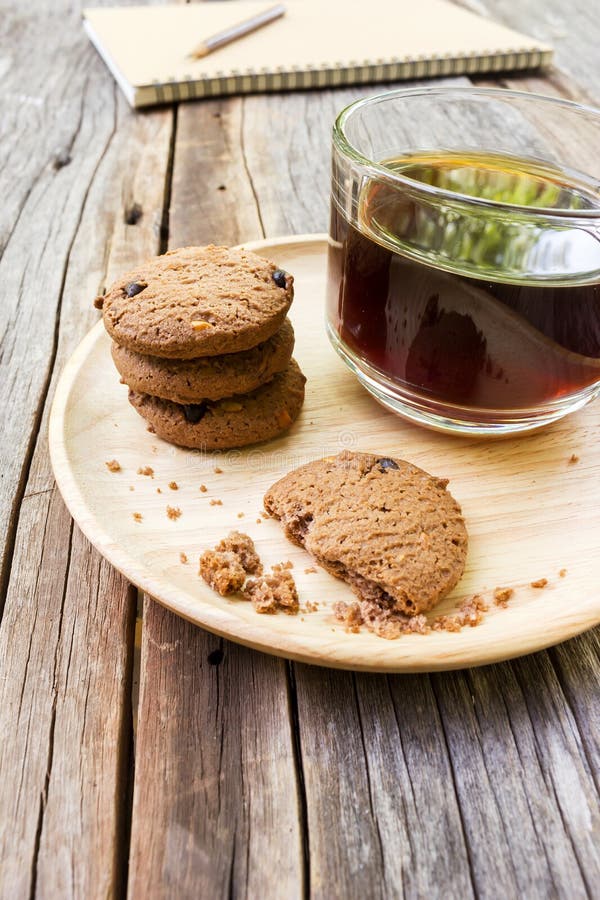 Le verre de café noir avec des gâteaux aux pépites de chocolat sur en bois plat images stock Le verre de café noir avec des gâteaux aux pépites de chocolat sur en bois plat images stock