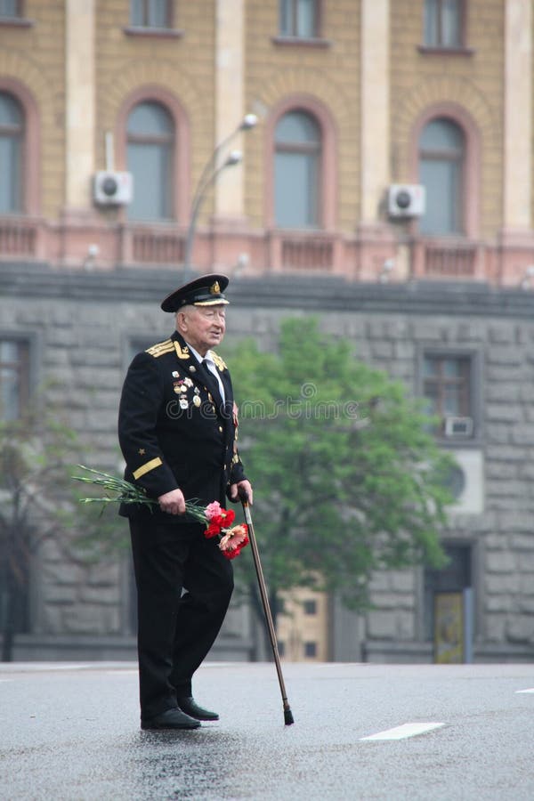 Le vieil homme inconnu le vétéran de la guerre avec des récompenses, avec des fleurs et dans un uniforme, dans le jour du cortège image stock Le vieil homme inconnu le vétéran de la guerre avec des récompenses, avec des fleurs et dans un uniforme, dans le jour du cortège image stock