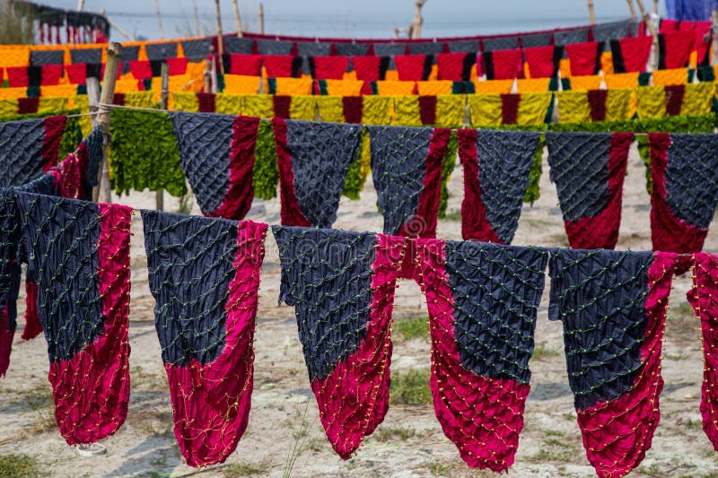 Waves of every color swaying in the wind , and a sweet scent of freshly cut fabric everywhere. It seems the waves of color extended towards horizon. This scene is from Narayanganj's Araihajar Banti, Rupganj's Noagaon and Chanpara villages.A village which once was surrounded by scarcity, its children could not go to school as their parents were unable to pay the fees, now changed the scenario up side down and become a role model for the whole country. Now the families of these villages associated with batik business are earning Tk 2,160 crores annually.Banti village is only 32 km away from Dhaka. All those three villages including Banti are now famous for batik. Batik cloths of three villages are sold in Banti Bazar. Abdul Hai Bhuiyan, President of Banti Bazaar Traders Association, said that batik business started in this market in 1981. At present it has turned into a hub. There are 22 small and big markets on both sides of this hub. There are almost 2500 shops in these markets. Right now 1,500 shops are in operation. The rest of the shops will also open before the next holy month of Ramadan and Pahela Baisakh. Each of the 1,500 shops sell an average of Tk 40,000 worth of batik goods per day. According to that, there is a business of 180 crore rupees per month. And the annual business is 2 thousand 160 crore Taka.From dawn to dusk, the men and women of these villages are busy making batik. As far as the eye can see, cloths painted in various traditional designs are seen hanging on ropes. Residents of the village are dyeing clothes in the yard, side roads, land or open fields, some are blocking, others are drying wet clothes in the sun. Waves of every color swaying in the wind , and a sweet scent of freshly cut fabric everywhere. It seems the waves of color extended towards horizon. This scene is from Narayanganj's Araihajar Banti, Rupganj's Noagaon and Chanpara villages.A village which once was surrounded by scarcity, its children could not go to school as their parents were unable to pay the fees, now changed the scenario up side down and become a role model for the whole country. Now the families of these villages associated with batik business are earning Tk 2,160 crores annually.Banti village is only 32 km away from Dhaka. All those three villages including Banti are now famous for batik. Batik cloths of three villages are sold in Banti Bazar. Abdul Hai Bhuiyan, President of Banti Bazaar Traders Association, said that batik business started in this market in 1981. At present it has turned into a hub. There are 22 small and big markets on both sides of this hub. There are almost 2500 shops in these markets. Right now 1,500 shops are in operation. The rest of the shops will also open before the next holy month of Ramadan and Pahela Baisakh. Each of the 1,500 shops sell an average of Tk 40,000 worth of batik goods per day. According to that, there is a business of 180 crore rupees per month. And the annual business is 2 thousand 160 crore Taka.From dawn to dusk, the men and women of these villages are busy making batik. As far as the eye can see, cloths painted in various traditional designs are seen hanging on ropes. Residents of the village are dyeing clothes in the yard, side roads, land or open fields, some are blocking, others are drying wet clothes in the sun.