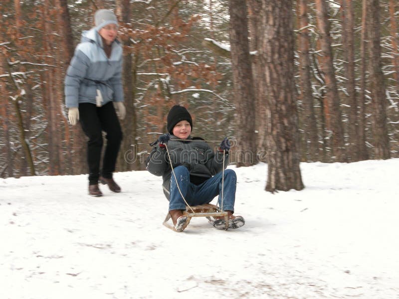 The boy slideing on sledge and the woman on snowy hill. The boy slideing on sledge and the woman on snowy hill
