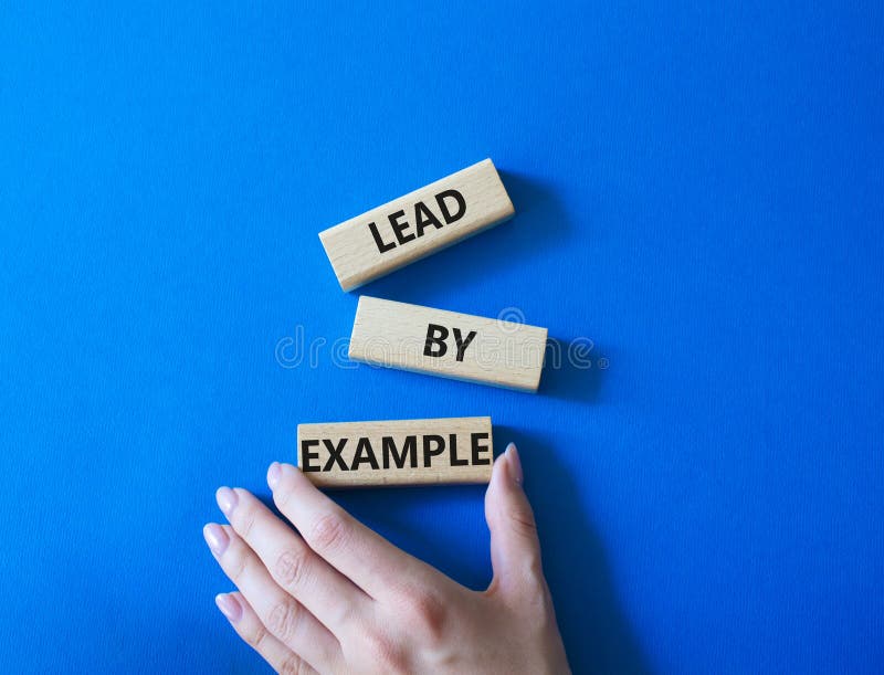 Exemplu de simbol. concept cuvânt plumb de exemplu, cuburi de lemn. mână om de afaceri. fundal albastru frumos. afaceri și royalty free stock photography