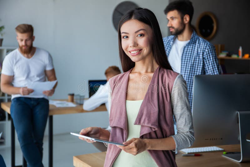 Leading her team to success. Confident young woman holding digital tablet and looking at camera with smile while her royalty free stock photo Leading her team to success. Confident young woman holding digital tablet and looking at camera with smile while her royalty free stock photo