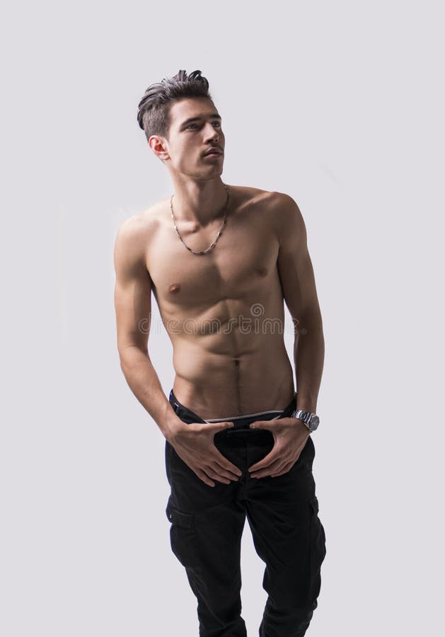 Lean athletic shirtless young man standing on light background