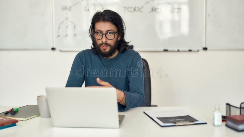 Learn Computer Programming online. Young focused bearded male teacher teaching computer science online through video stock image