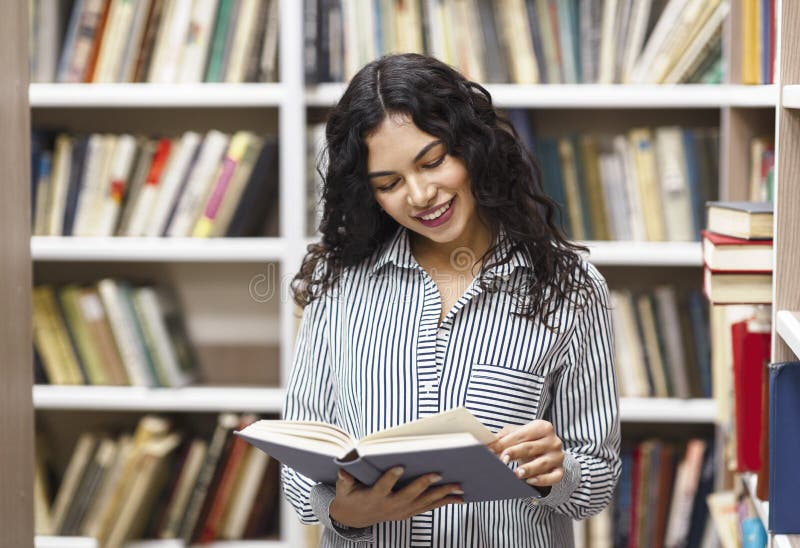 Smiling latina woman reading a book at library