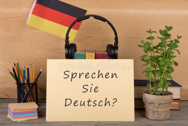 paper with text & x22;sprechen sie deutsch& x22;, flag of the Germany, books, headphones, pencils