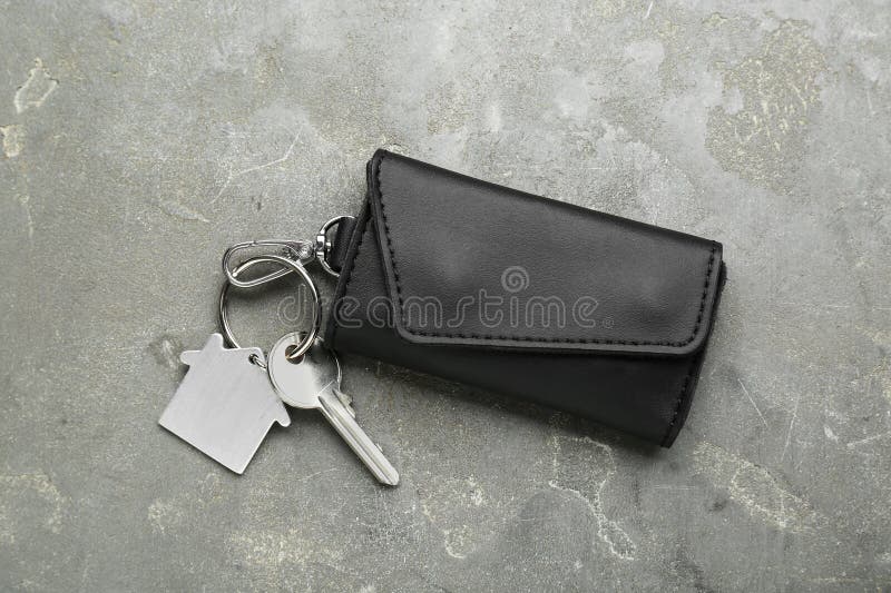 Leather case with key on grey textured table. Leather case with key on grey textured table