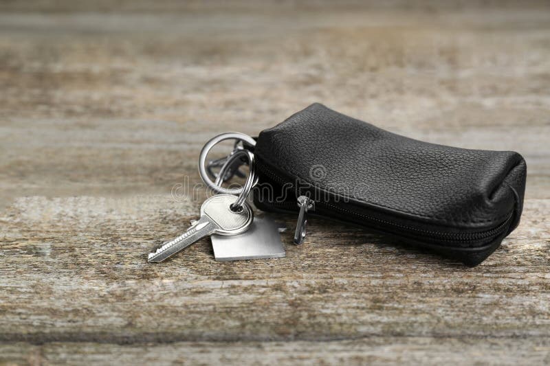 Leather case with key on old wooden table, closeup. Leather case with key on old wooden table, closeup.