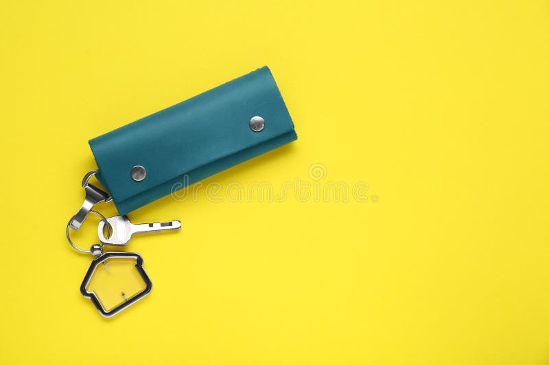 Leather case with key on yellow background, top view. Leather case with key on yellow background, top view.