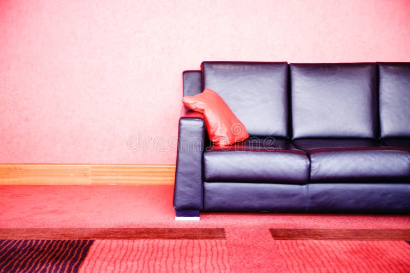 Red Leather Sofa Stands on the Brick Wall Background. Stock Image