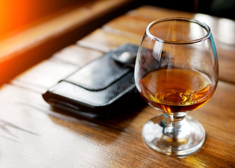 Leather wallet, red wine glass and cash spread out a table, concept of alcohol abuse and waste of money stock photo Leather wallet, red wine glass and cash spread out a table, concept of alcohol abuse and waste of money stock photo
