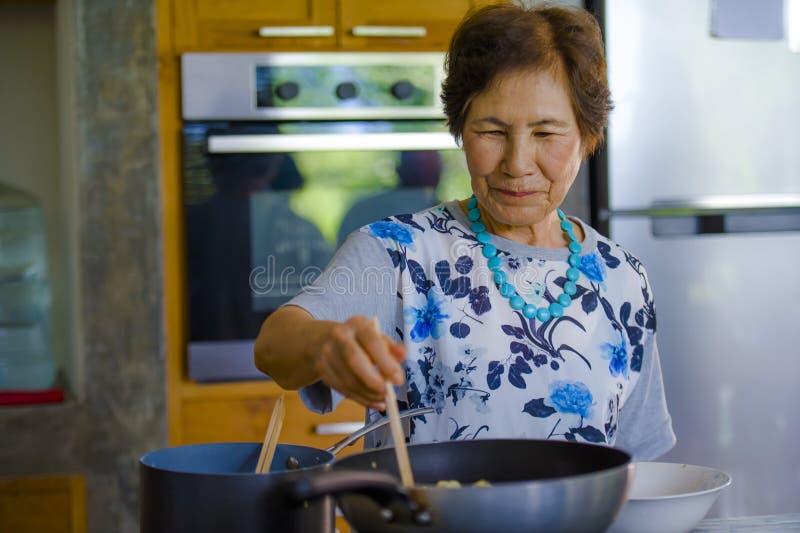 Lebensstilporträt der älteren glücklichen und süßen asiatischen japanischen Frau im Ruhestand, welche zu Hause die Küche allein o stockfoto Lebensstilporträt der älteren glücklichen und süßen asiatischen japanischen Frau im Ruhestand, welche zu Hause die Küche allein o stockfoto