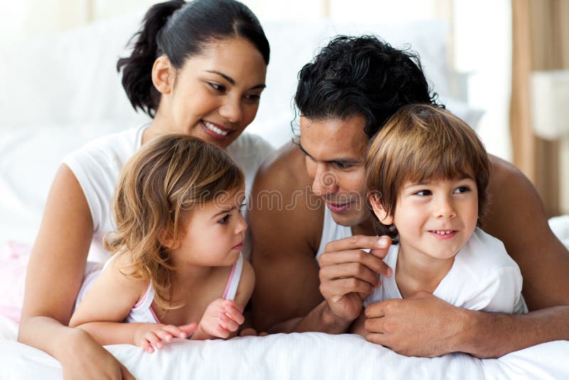 Lebhafte Familie, die Spaß hat, auf Bett zu liegen