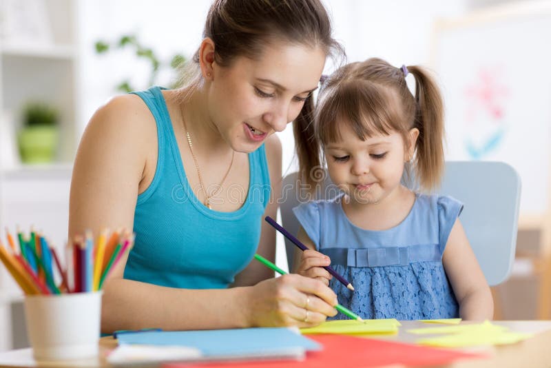 Lecciones del dibujo de la muchacha del maestro de jardín de infancia y del niño en la escuela imagen de archivo Lecciones del dibujo de la muchacha del maestro de jardín de infancia y del niño en la escuela imagen de archivo