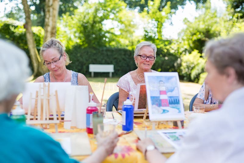 Lección al aire libre en el parque, señoras del arte que se sientan en la tabla y que aprenden pintar imágenes fotografía de archivo Lección al aire libre en el parque, señoras del arte que se sientan en la tabla y que aprenden pintar imágenes fotografía de archivo