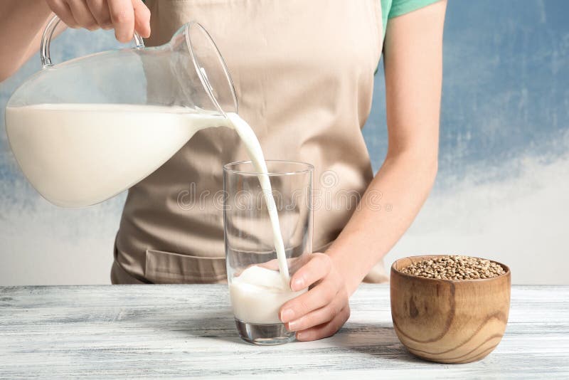Leche de colada del cáñamo de la mujer en el vidrio en la tabla imagenes de archivo Leche de colada del cáñamo de la mujer en el vidrio en la tabla imagenes de archivo