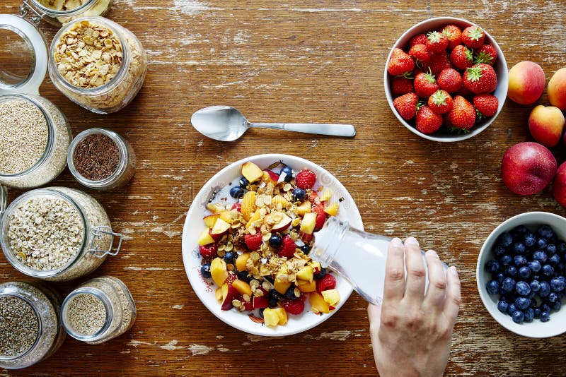 Leche de colada de la mano de la escena del desayuno en la nutrición orgánica de la forma de vida sana del muesli foto de archivo Leche de colada de la mano de la escena del desayuno en la nutrición orgánica de la forma de vida sana del muesli foto de archivo