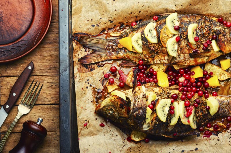 Leckerer Kruzier gebraten mit Kiwi und Mango. Fischkarpfen mit Früchten und Beeren in Backform