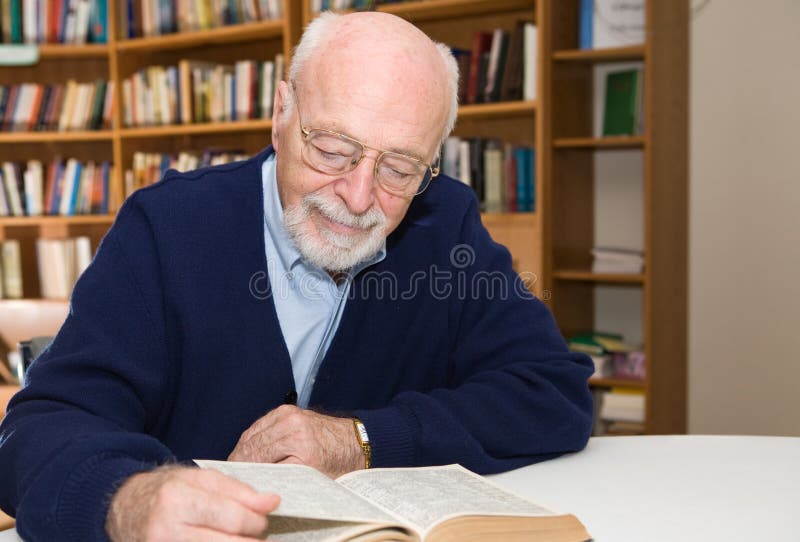 Senior man enjoys a good book in the library. Horizontal view with room for text. Senior man enjoys a good book in the library. Horizontal view with room for text.