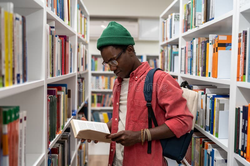 Lecteur passionné étudiant africain américain type choisir des manuels de recherche dans la bibliothèque universitaire. photos stock