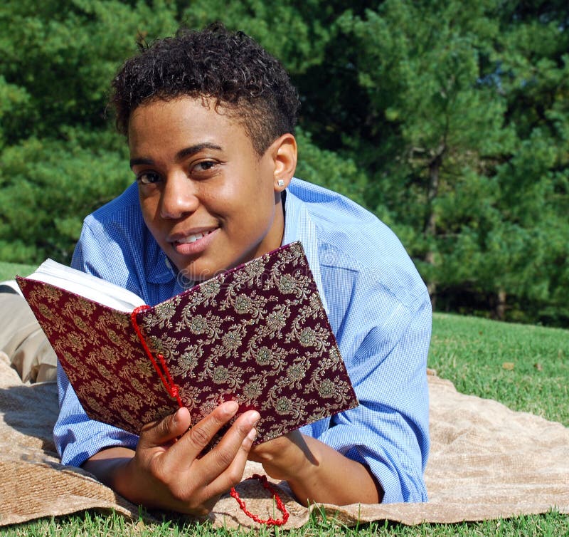 A woman reads an ornately decorated book while relaxing in the park. A woman reads an ornately decorated book while relaxing in the park.