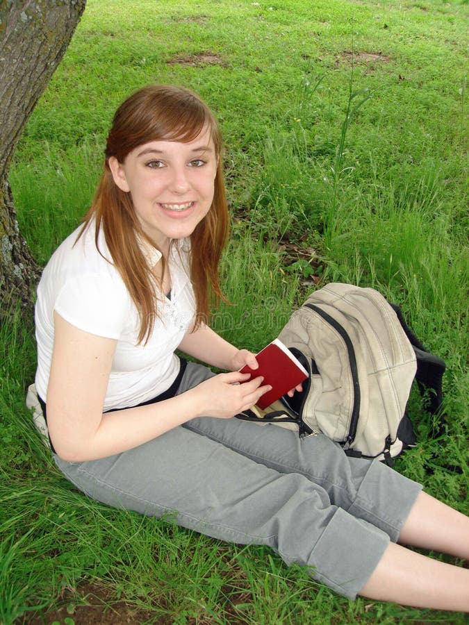 A teenage girl reads by a tree. A teenage girl reads by a tree.