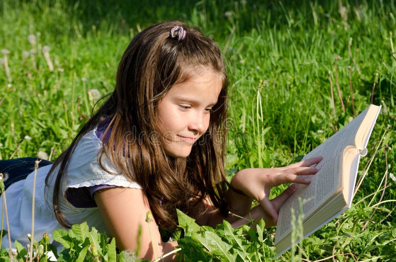 Young girl lying in summer field and reading a book. Young girl lying in summer field and reading a book