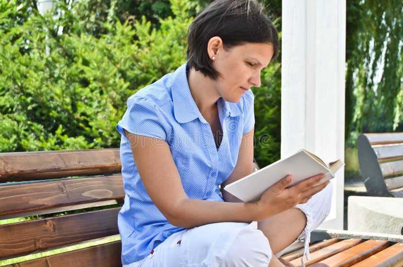 Woman sitting on the bench and reading a book. Woman sitting on the bench and reading a book