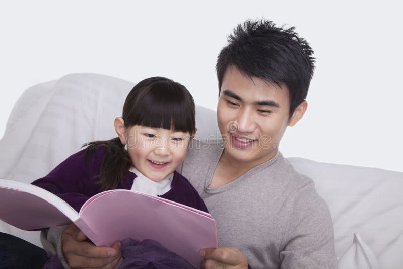 Lectura del padre y de la hija en el sofá fotos de archivo libres de regalías Lectura del padre y de la hija en el sofá fotos de archivo libres de regalías