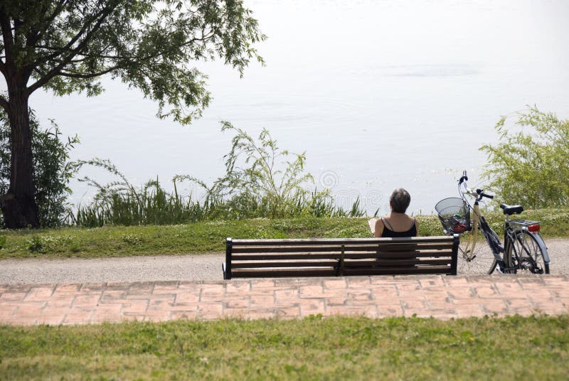 A woman reads on a park bench. A woman reads on a park bench