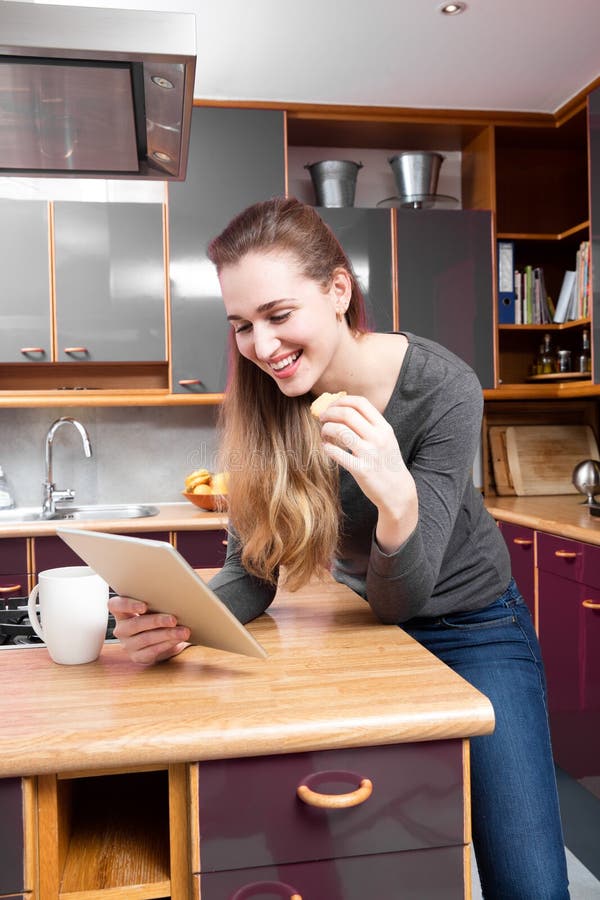 Lectura magnífica sonriente de la mujer joven en tecnología casera relajante foto de archivo libre de regalías