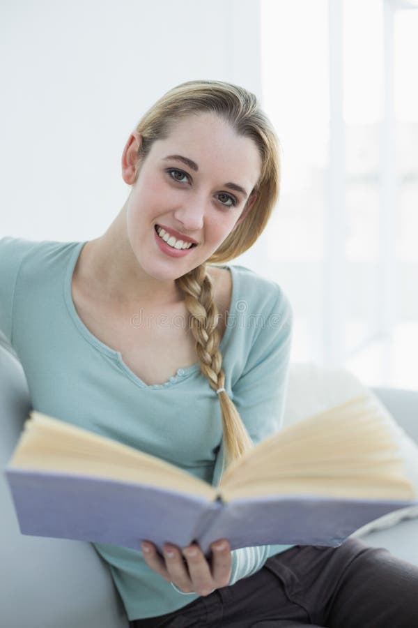 Lectura relajante de la mujer tranquila linda un libro que se sienta en la sala de estar foto de archivo Lectura relajante de la mujer tranquila linda un libro que se sienta en la sala de estar foto de archivo